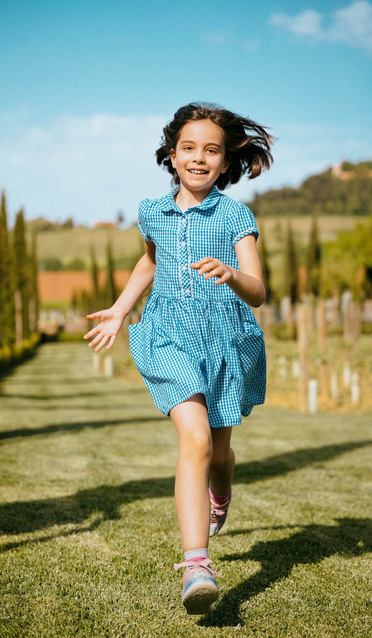 Young girl running in a blue dress through a field