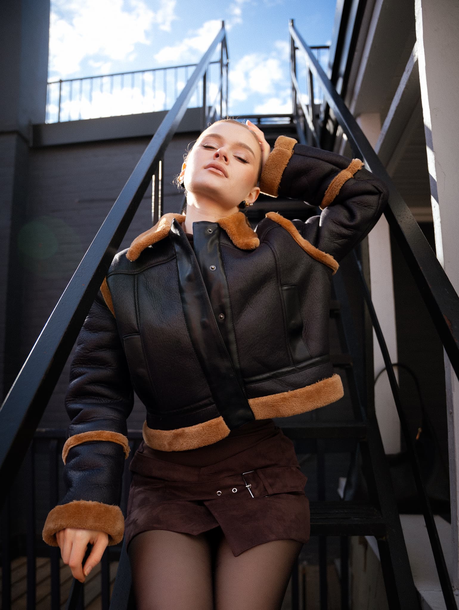 Woman lounging on outdoor metal stairs, hand behind head