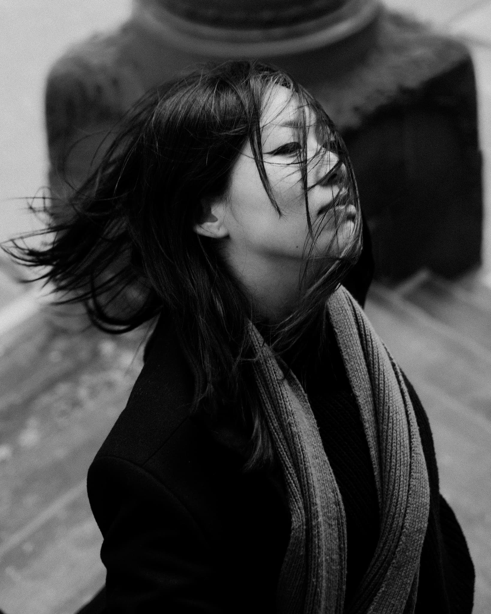 Black-and-white portrait of a woman with windblown hair and scarf