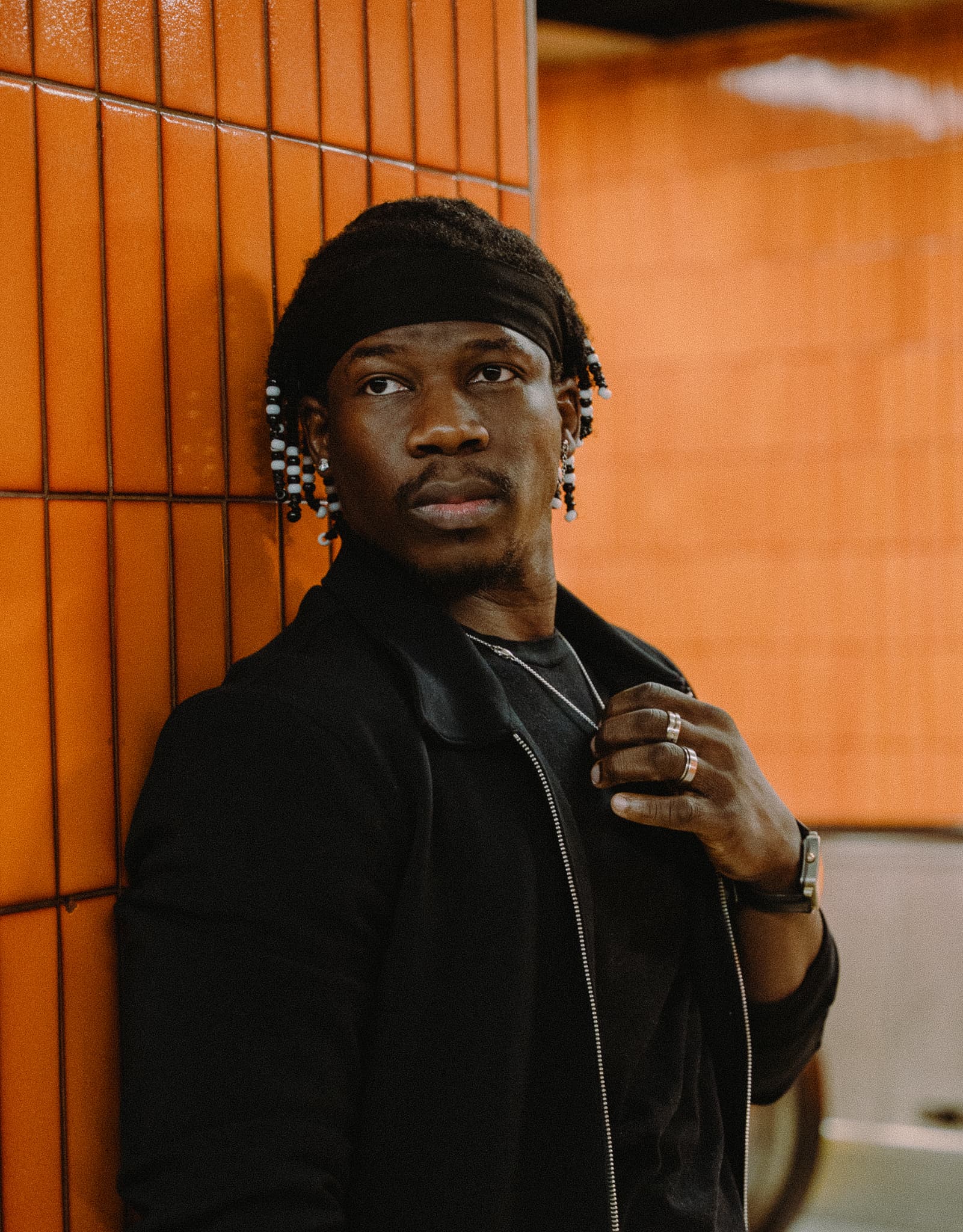 Man in black beside an orange tiled wall